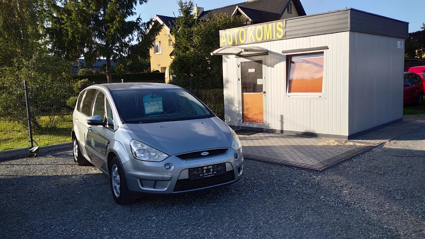 Biuro komisu z napisem Auto Komis i samochód przed wejściem
